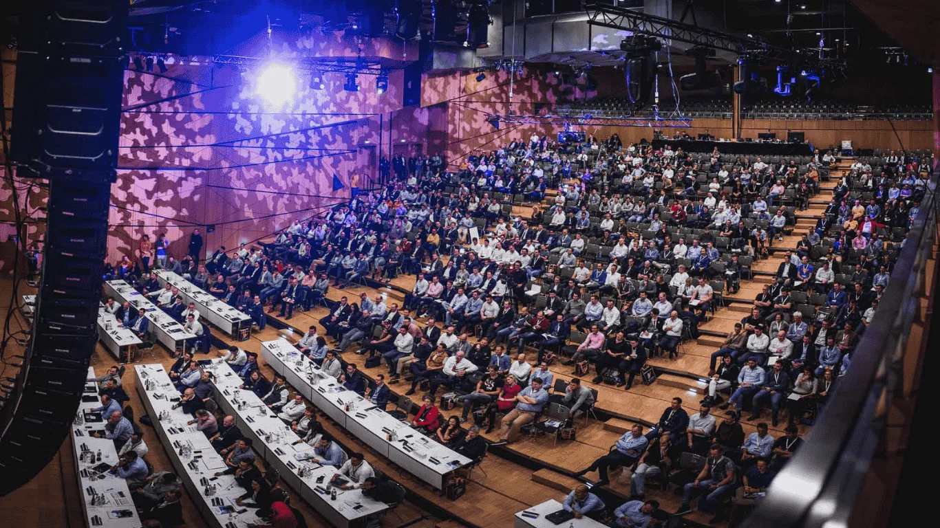 Immopreneur Kongress Veranstaltungssaal mit hunderten Teilnehmern, Bühne mit Bildschirmen und blauer Beleuchtung