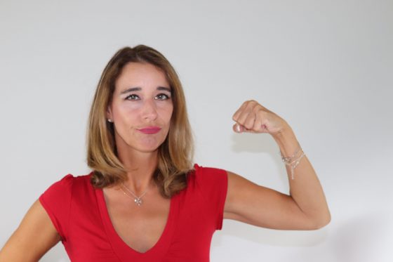 Frau in rotem Oberteil mit Flexpose, demonstriert Stärke und Selbstbewusstsein
