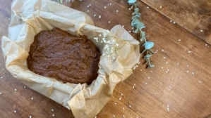 Schokoladenkuchen-Teig in mit Backpapier ausgelegter Form, dekoriert mit Eukalyptuszweig und Blüten