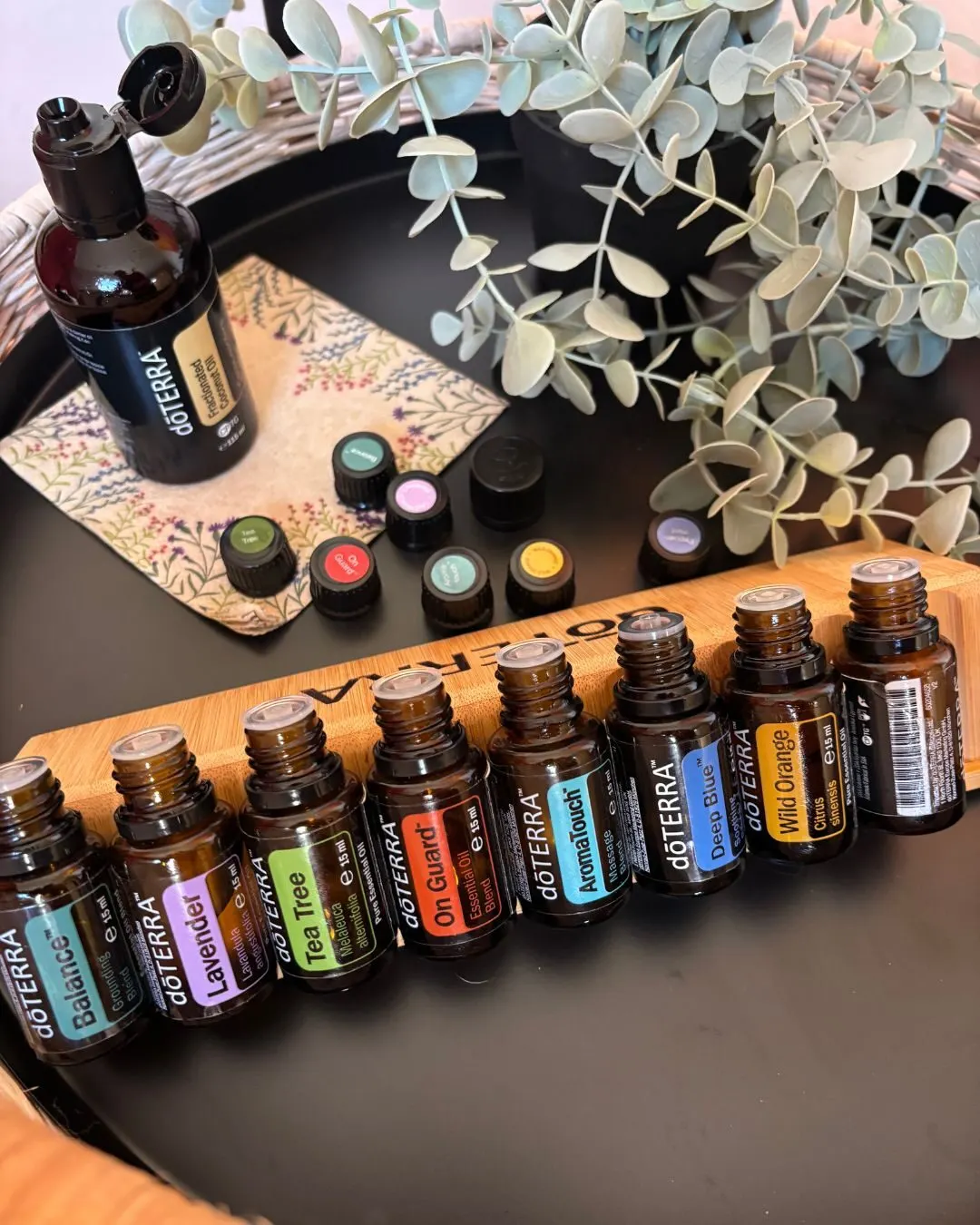 Ernährungsberatung – Coaching für anti-entzündliche Ernährung 5 dōTERRA ätherische Öle in verschiedenen Farben mit Diffuser, Eukalyptus und Perlenarmband auf Holz