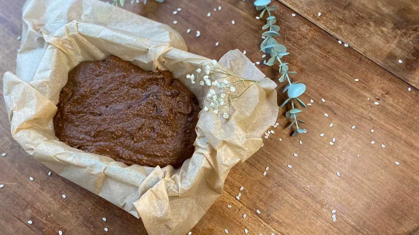 Ernährungsberatung – Coaching für anti-entzündliche Ernährung 8 Schokoladenkuchen-Teig in mit Backpapier ausgelegter Form, dekoriert mit Eukalyptuszweig und Blüten