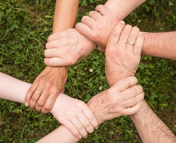 Mehrere Hände bilden Kreis auf grüner Wiese