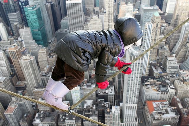 Person klettert über Stahlseil mit Cityscape-Hintergrund
