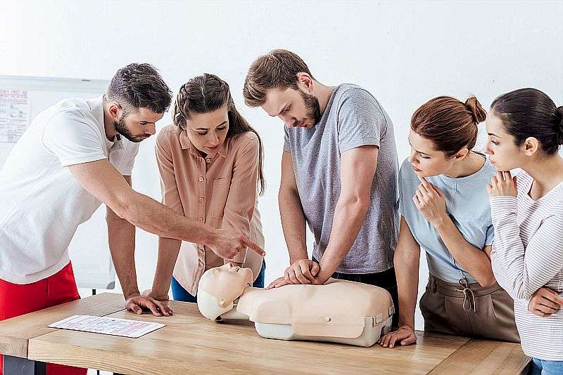 Erste Hilfe Kurs – Videotraining mit Teilnahmebescheinigung 4 Erste-Hilfe-Schulung mit Gruppe von Personen bei CPR-Übung an Puppe
