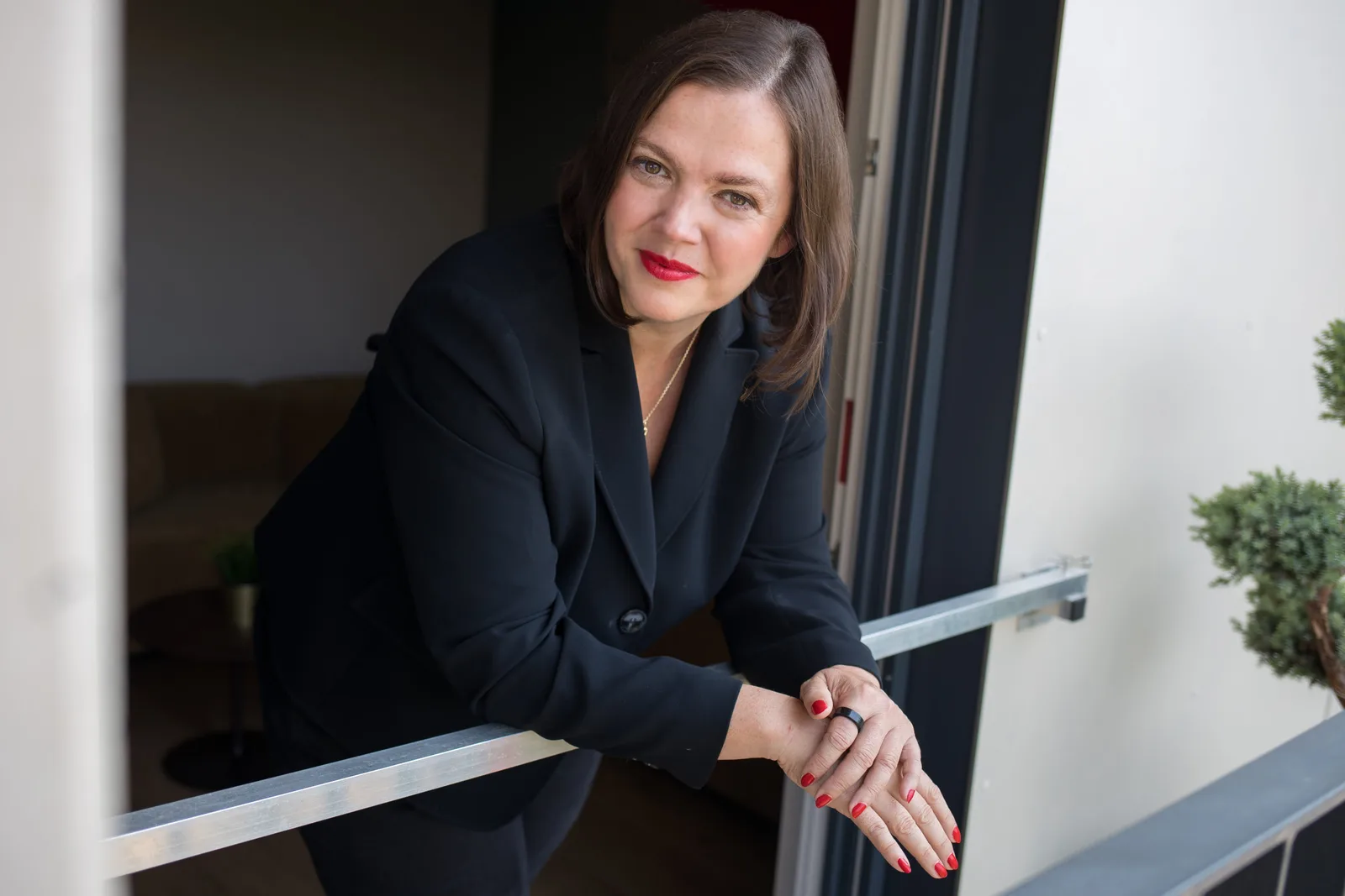 Petra Binder an Geländer modernes Büro-Interieur – Über mich Excellence Strategy Academy