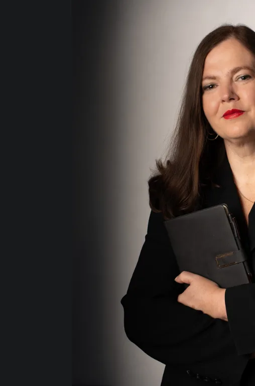 Petra Binder Nahaufnahme in schwarzem Anzug mit Dokumentenmappe