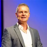 Experten-MasterClass – Webinar zur Leadgewinnung von Dawid Przybylski 8 Porträt eines Mannes im Anzug vor blauem Hintergrund