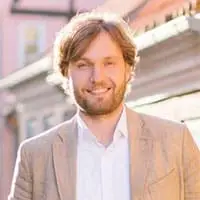 Experten-MasterClass – Webinar zur Leadgewinnung von Dawid Przybylski 9 Porträt eines Mannes in hellem Anzug vor urbaner Kulisse