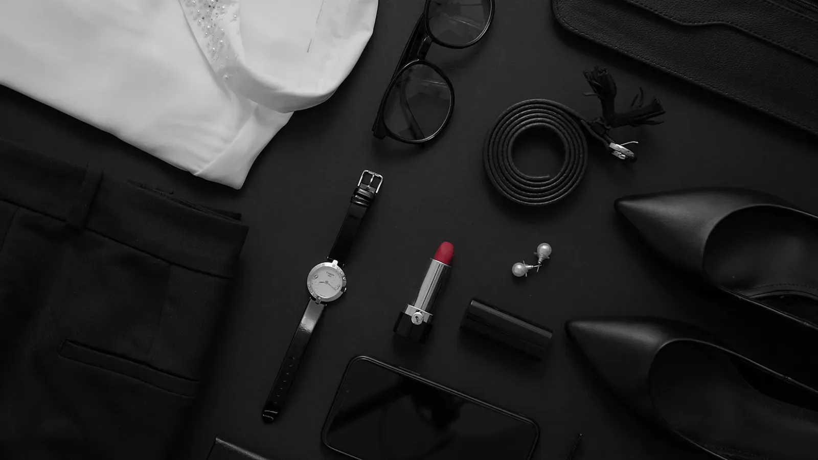 Stilvolle schwarz-weiße Mode-Accessoires einer Business Frau mit weißer Bluse, Brille, Gürtel, Uhr, Lippenstift und Handy