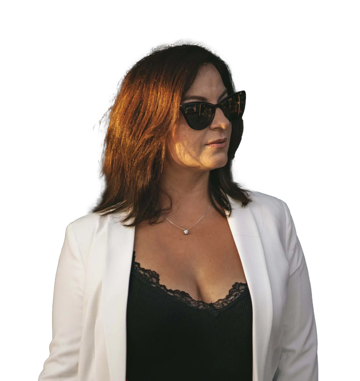Frau mit rötlich-braunen Haaren, weißem Blazer und schwarzem Lace-Top, trägt Sonnenbrille