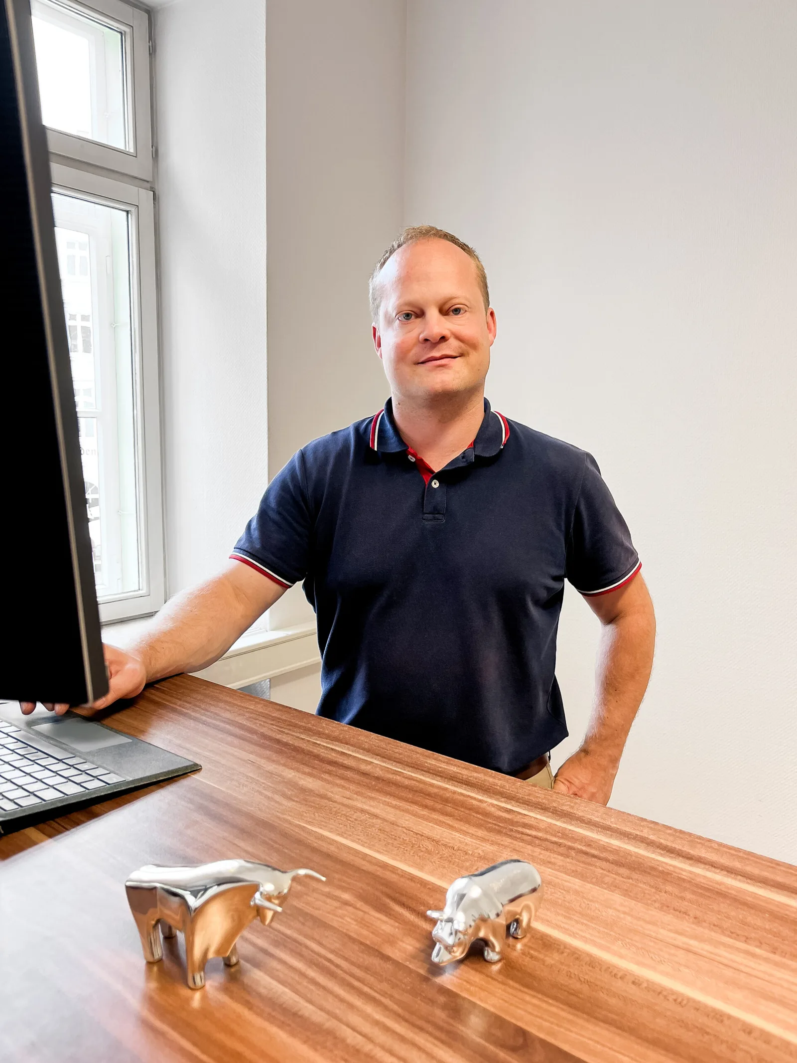 Fit für PKV – Videokurs zur PKV von Bernd Krause 7 Autor Bernd Krause an Schreibtisch mit Computer, Holztisch und Dekofiguren, Bürofenster