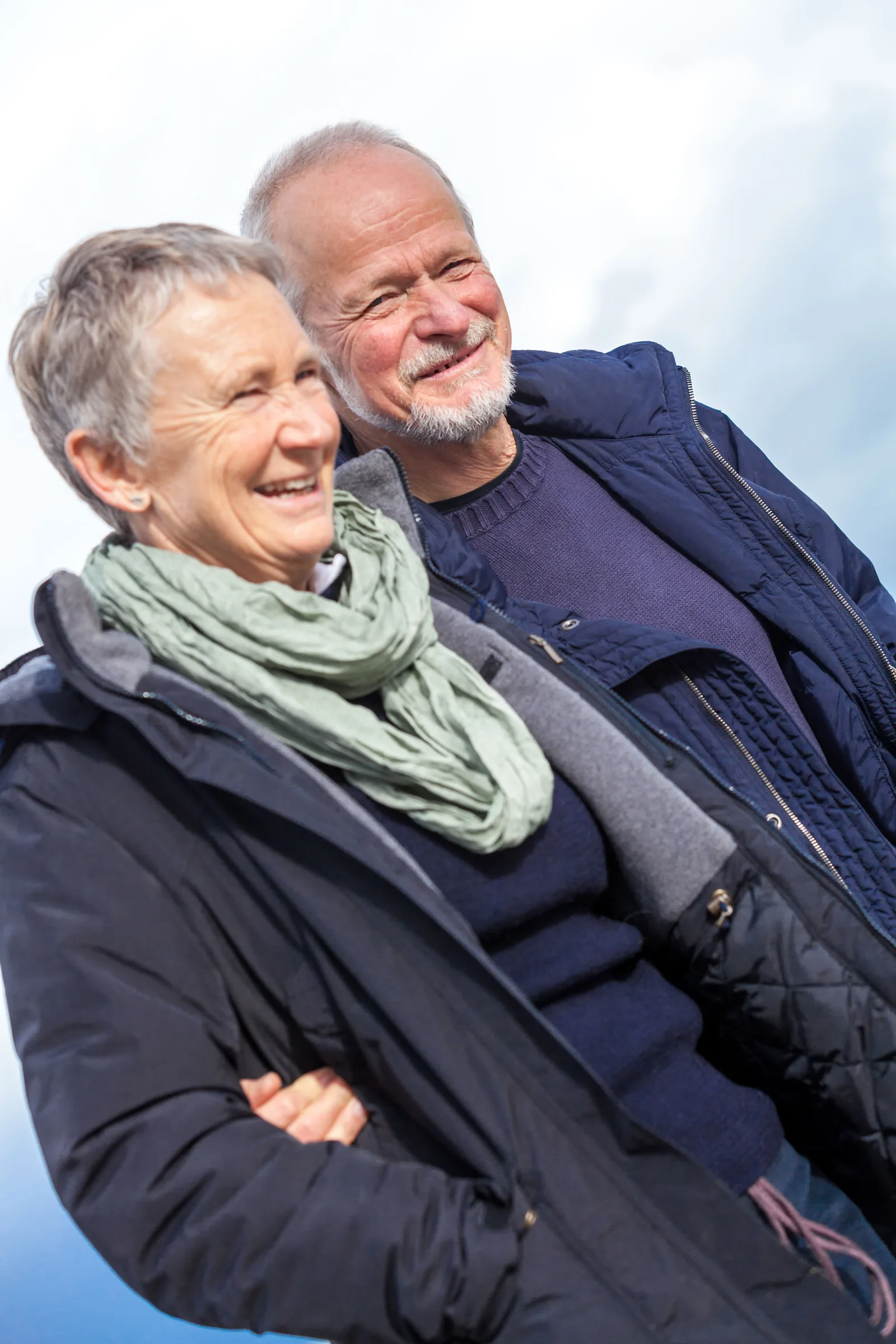 Zwei glückliche Senioren über 65 Jahre im Freien, Frau vorn, Mann dahinter, beide lachen
