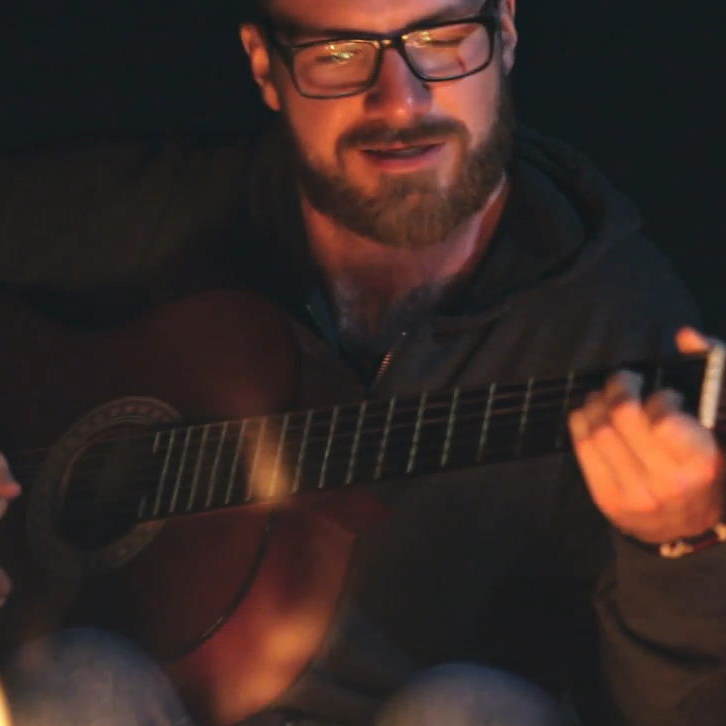 Gitarrist mit Brille beim Spielen in warmem Licht