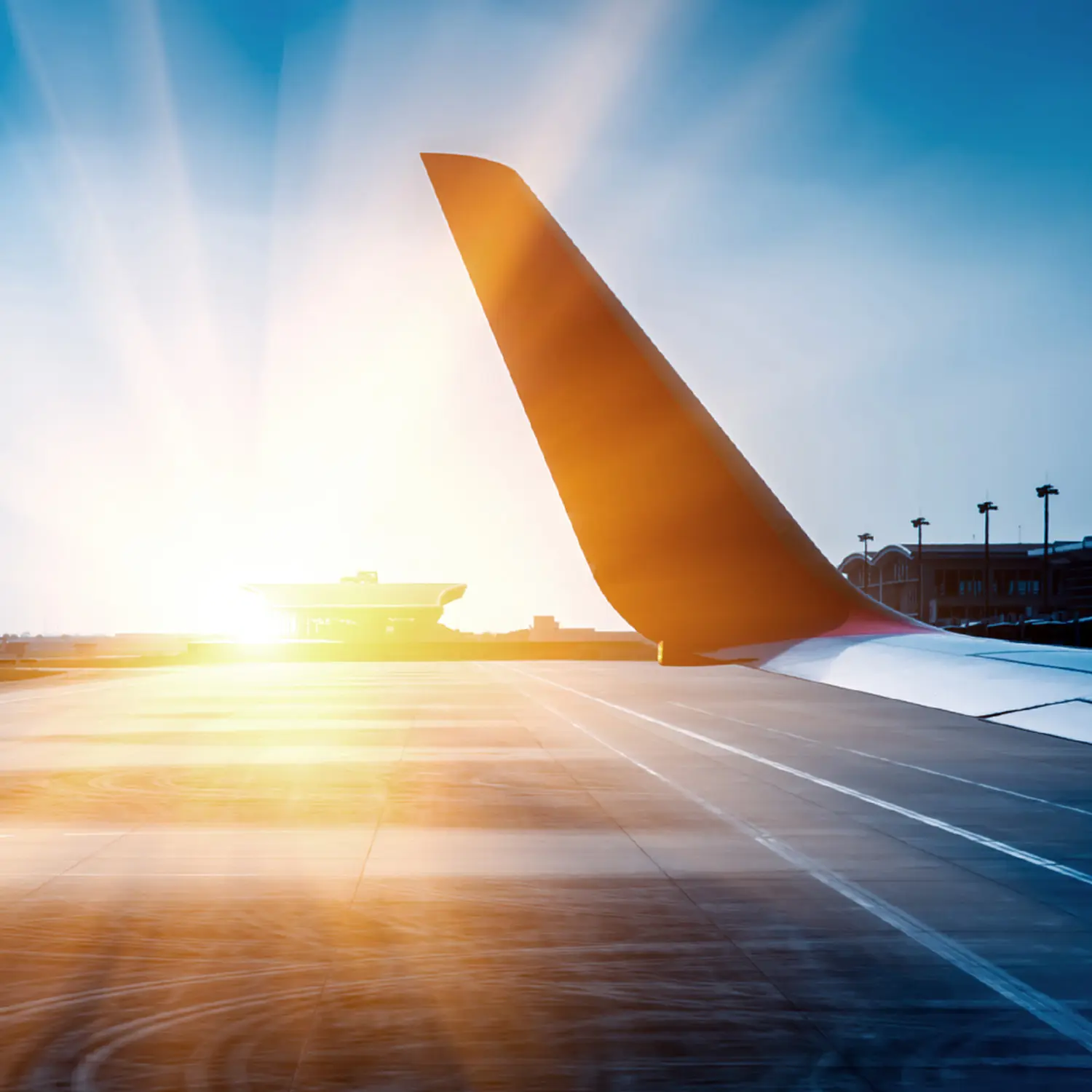 Flugzeugflügel in Orange vor blauem Himmel bei Sonnenuntergang, Flughafen