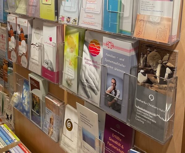 Nahaufnahme einer Wandmontage mit verschiedenfarbigen Flyern und Informationsmaterialien in Behältern