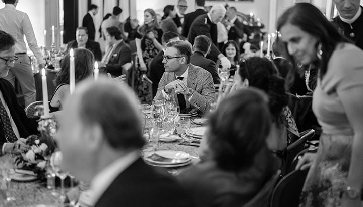 Menschen beim formellen Dinner an Tisch mit Kerzen und Besteck, schwarz-weiß