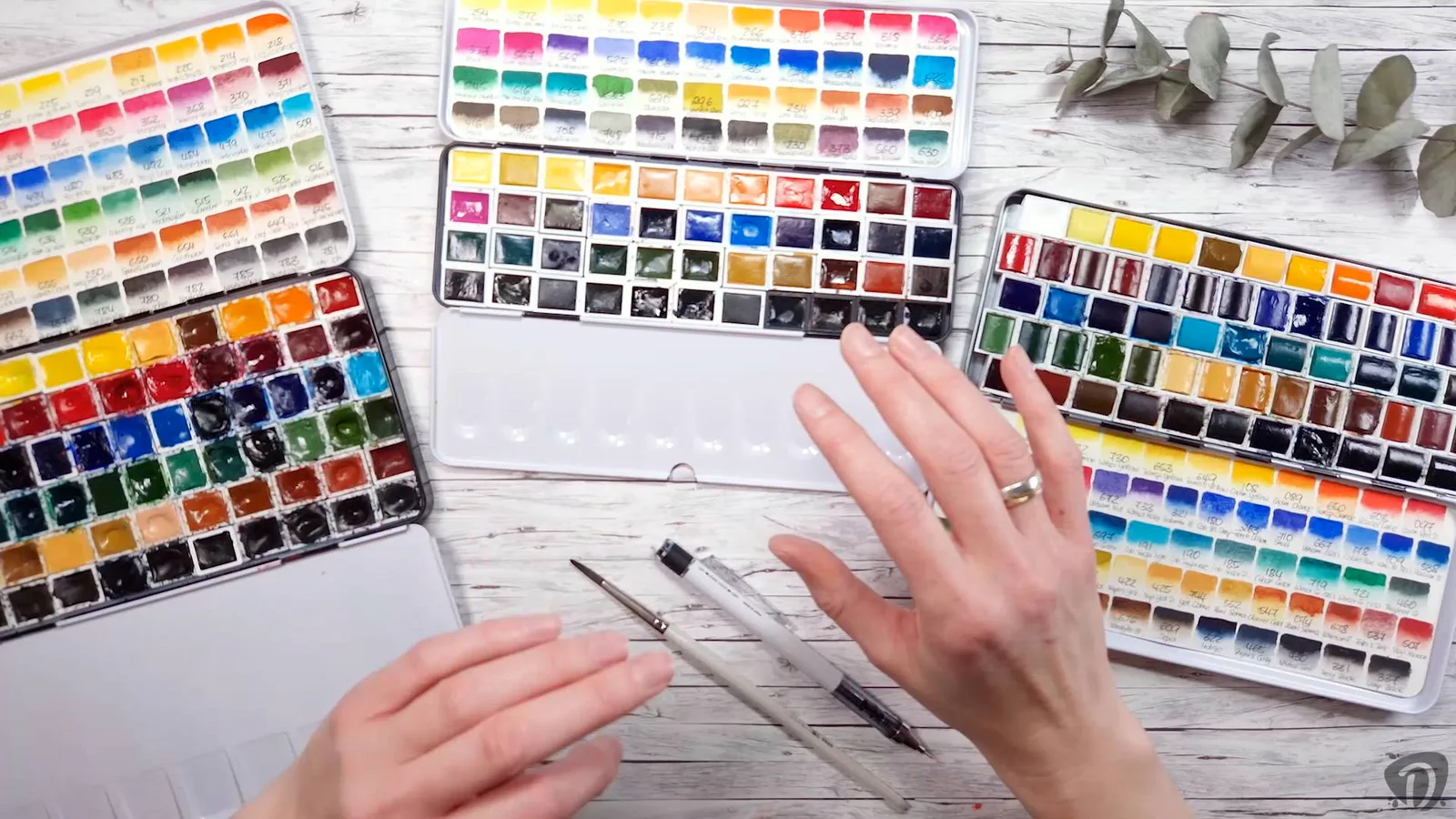 Overhead-Aufnahme von Aquarellfarben-Paletten, Mischbeispielen und Pinseln