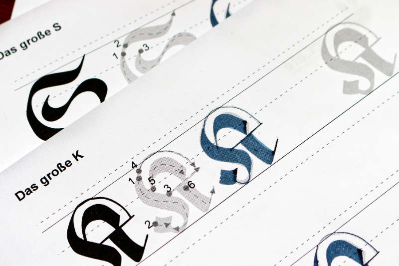 Nahaufnahme Übungsblätter mit Frakturschrift-Buchstaben K und S zum Nachschreiben