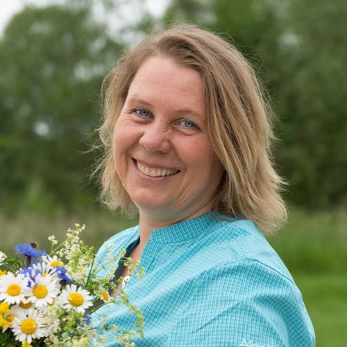 Heike Engel, Frau mit blondem Haar in blauem Hemd mit Blumenvase
