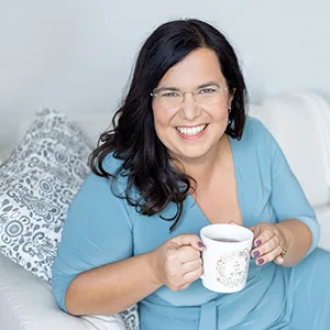 Frau mit schwarzen langen Haaren in blauem Shirt mit weißer Tasse