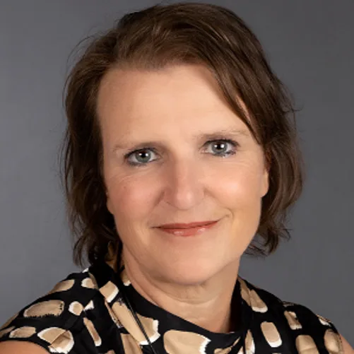 Andrea Reischmann, Frau mit braunem Haar vor grauem Hintergrund