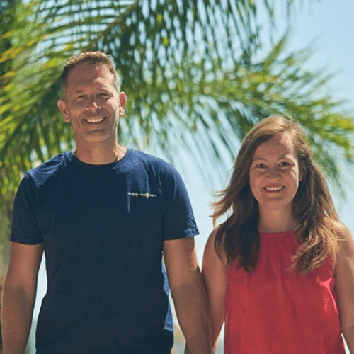 Anna Nguyen und Dr. Eike Brodt, Mann in dunkelbauem T-Shirt und Frau in rotem Top vor Palmenbäumen