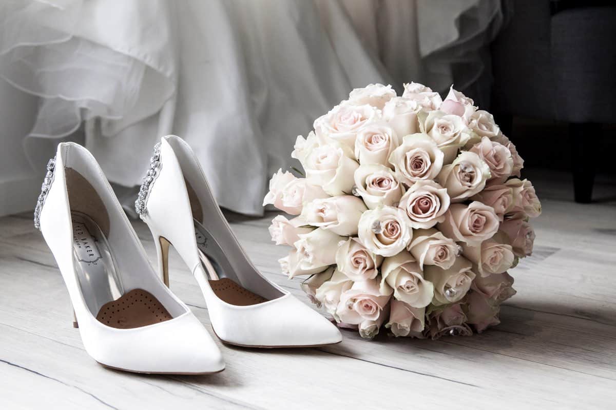 Brautschuhe in Weiß mit Strass-Details und Brautstrauß aus Rosen in Creme und Rosa-Tönen