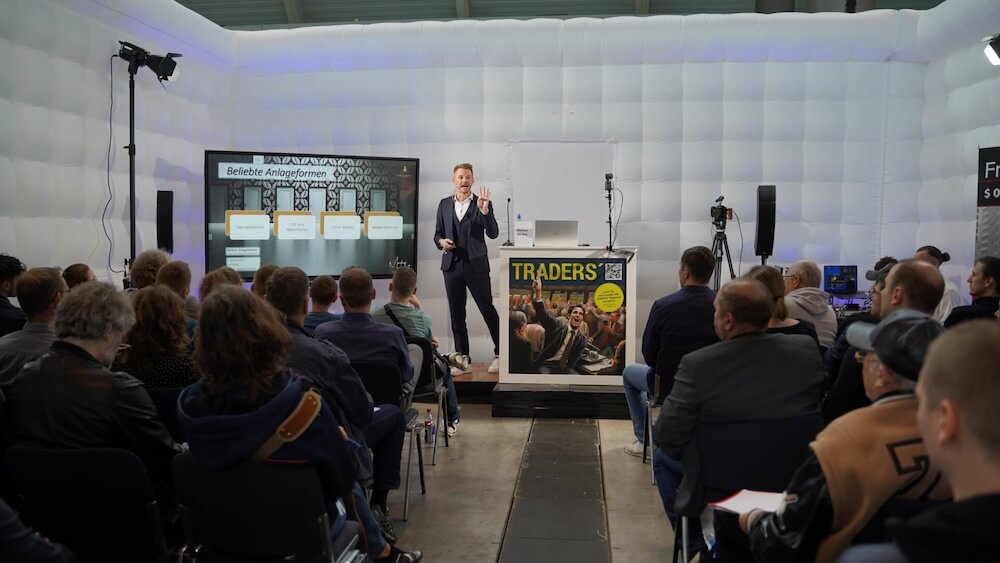 Markus Herfert hält Vortrag auf Invest Stuttgart mit Publikum, Bühne mit Grafiken zu Anlagformen