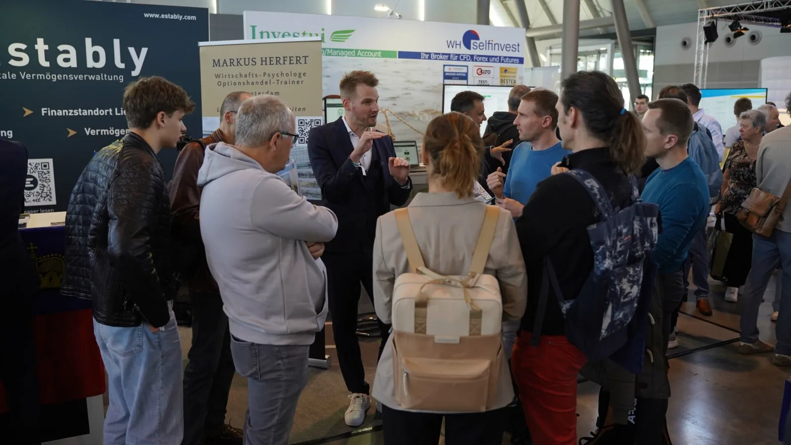 Markus Herfert im Gespräch mit Besuchern an Messestand mit Bannern von stably und Selfinvest, Gewinne generieren