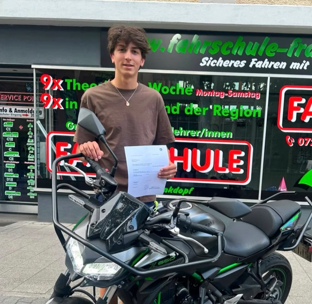Motorrad-Fahrschüler mit bestandener Führerscheinprüfung vor Motorrad und Fahrschule Frank Dopf Filiale