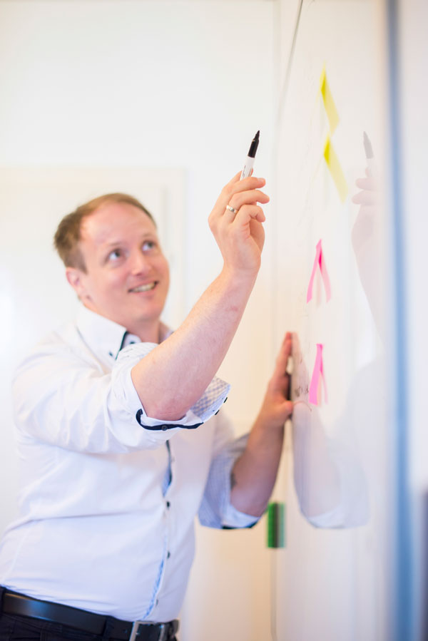 Stefan schreibt mit Marker auf Flipchart mit bunten Notizzetteln