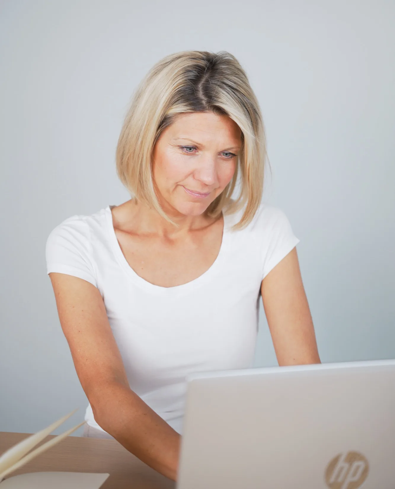 Frau in weißem Shirt schaut auf Laptop-Bildschirm während Online-Training