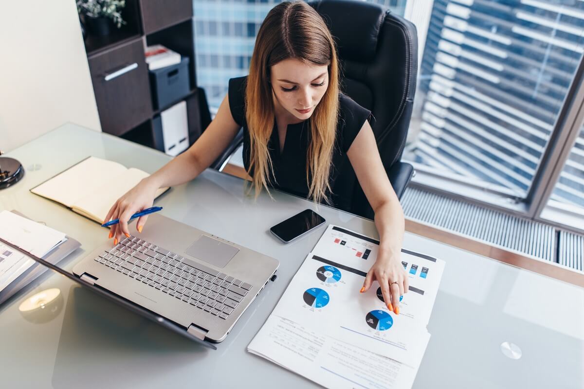 Frau im Büro mit Laptop analysiert PDF- und Excel-Vorlagen für Projekte