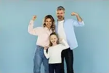 Ganzheitliches Online-Programm für Eltern – Erziehungskurs 10 Familie mit Eltern und zwei Kindern zeigt Muskeln vor blauem Hintergrund
