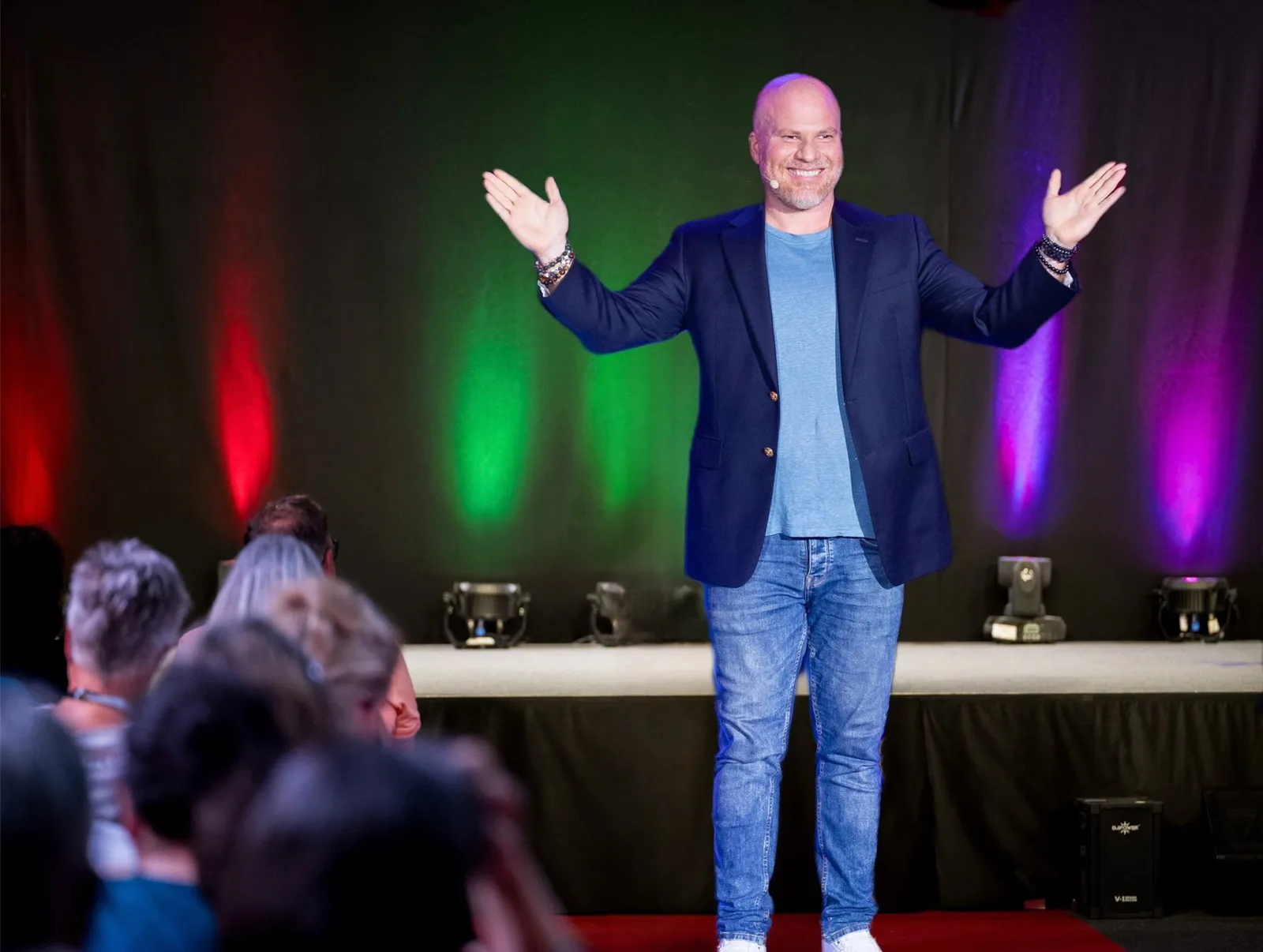 Ralf Haase als Speaker auf Bühne vor Publikum mit Armen ausgebreitet