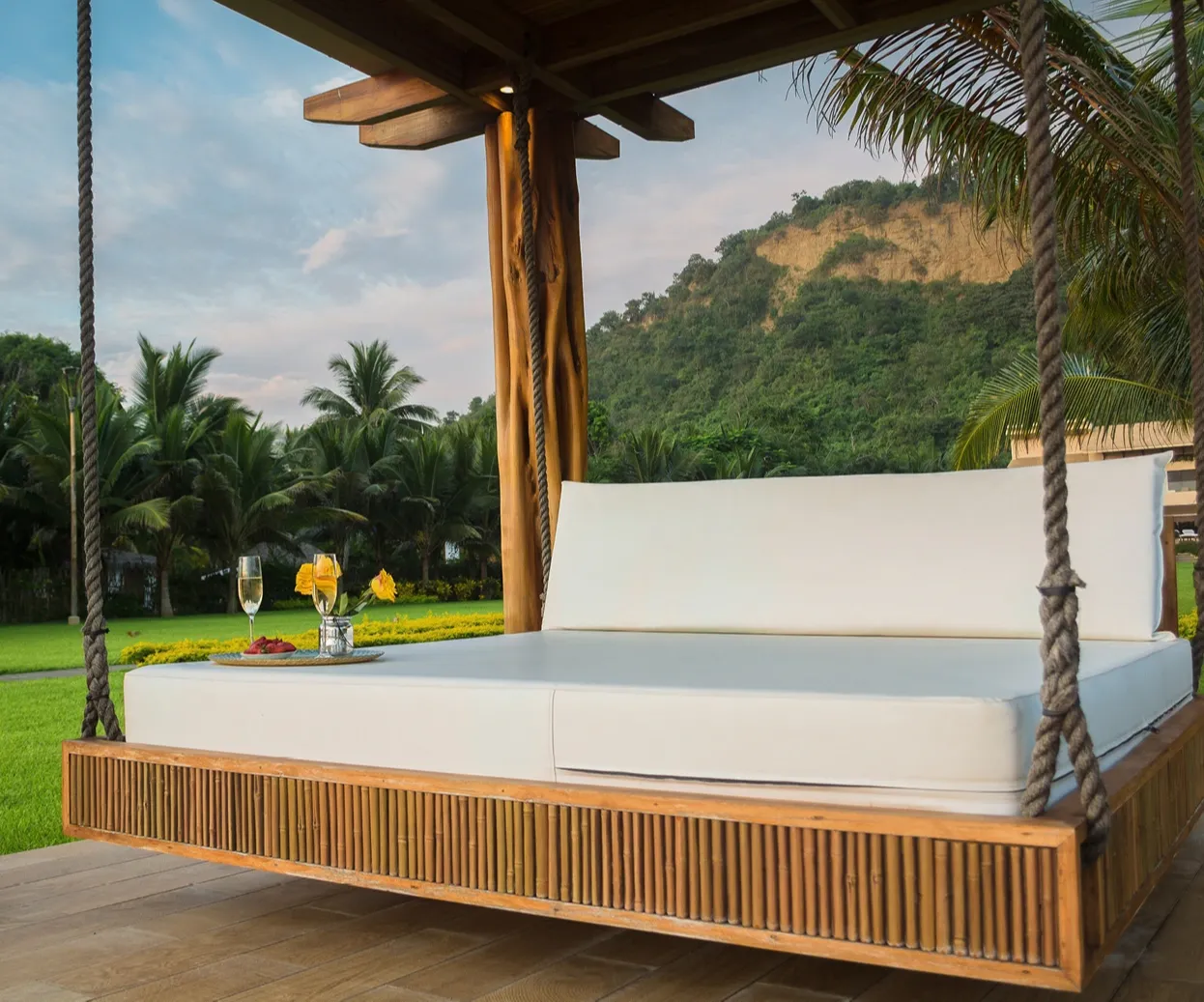 Loungebett mit Pergola und Glas Champagne, tropische Gartenlandschaft