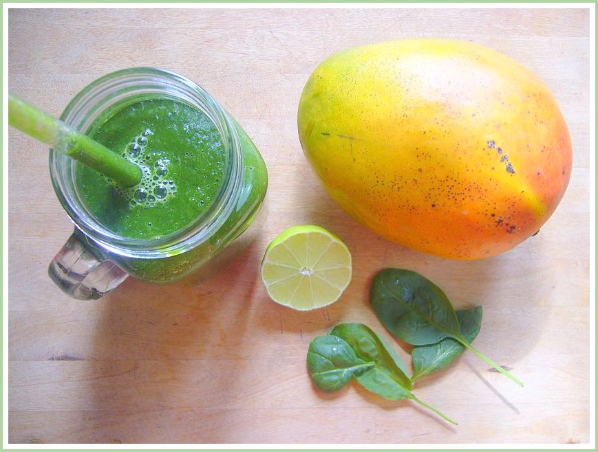 Mango-Limetten-Spinat-Smoothie im Glas mit Mango und Spinatblättern