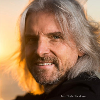 Porträt von Michael Wieden mit langen grauen Haaren und Bart, warmgetönte Beleuchtung