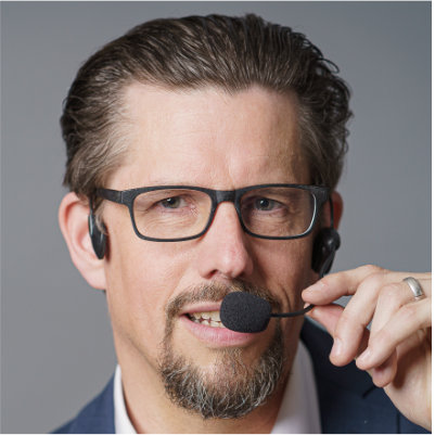 Porträt von Markus Kamps mit Brille und Headset-Mikrofon
