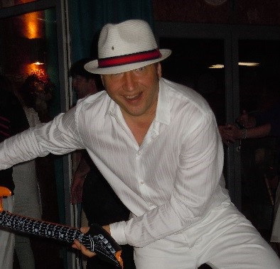 Mann in weißem Hemd und Hut mit Gitarre