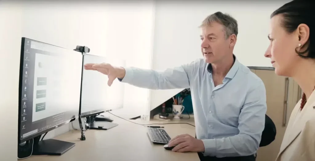Zwei Geschäftsleute besprechen Designkonzept am Monitor mit Kamera-Setup im Büro