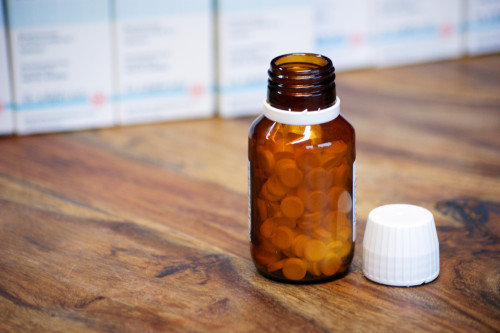Braune Flasche mit Schüßler Salz-Tabletten auf Holztisch