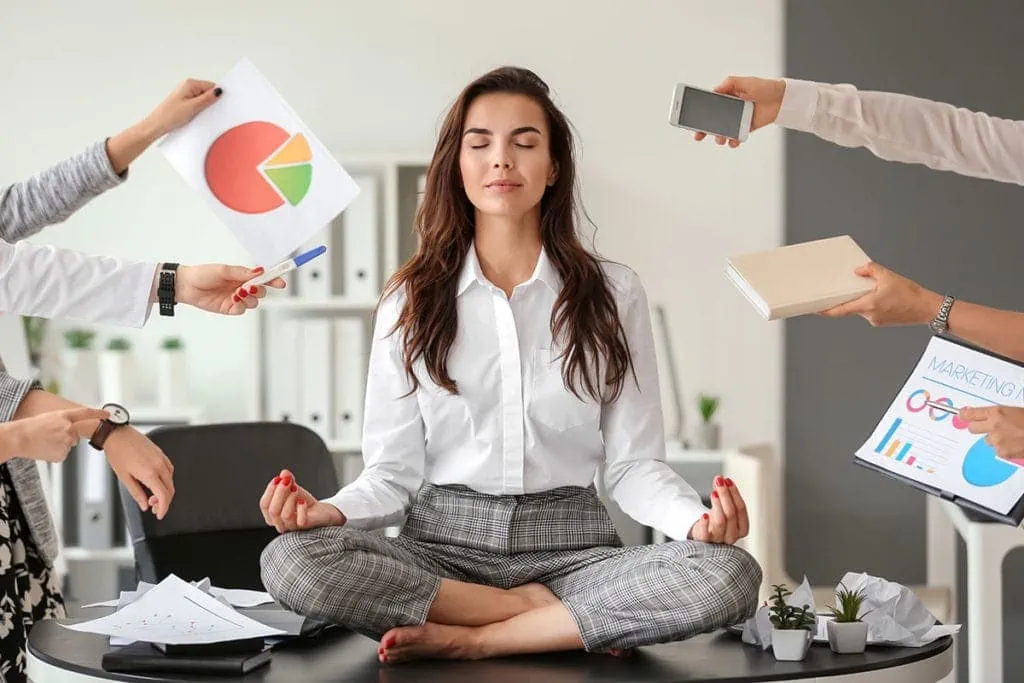Frau in Meditation umgeben von geschäftlichen Anforderungen – Hatha Yoga Präventionskurs