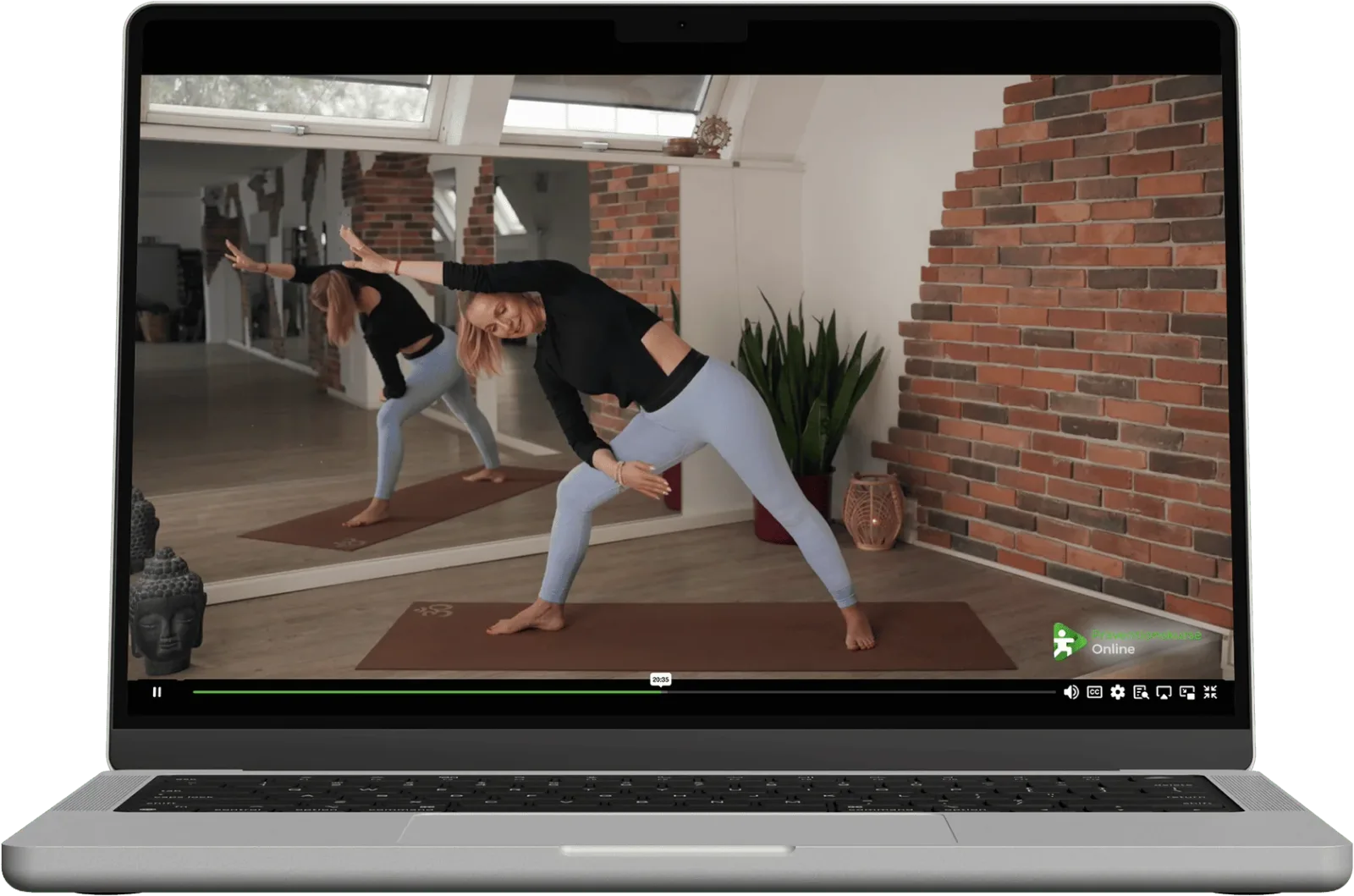 Zwei Frauen führen Yoga-Bewegungen während Online-Kurs am Laptop durch