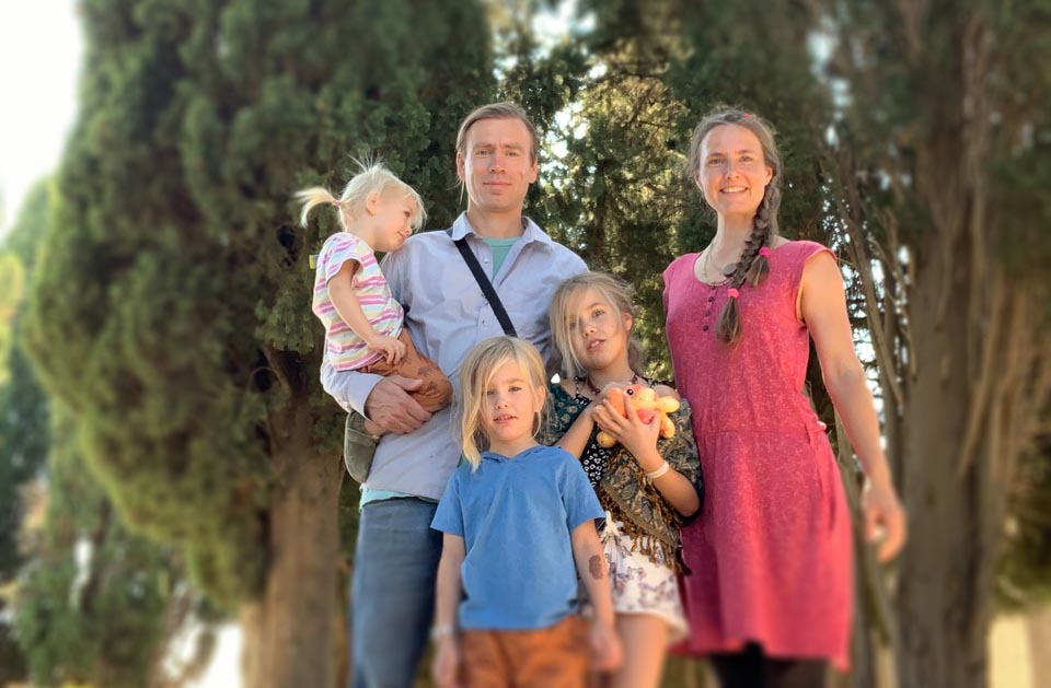 Fünfköpfige Familie zwischen Bäumen, bunte Kleidung, natürliche Pose