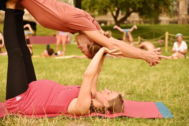 Vater macht Acro-Yoga mit Tochter auf grünem Rasen im Park
