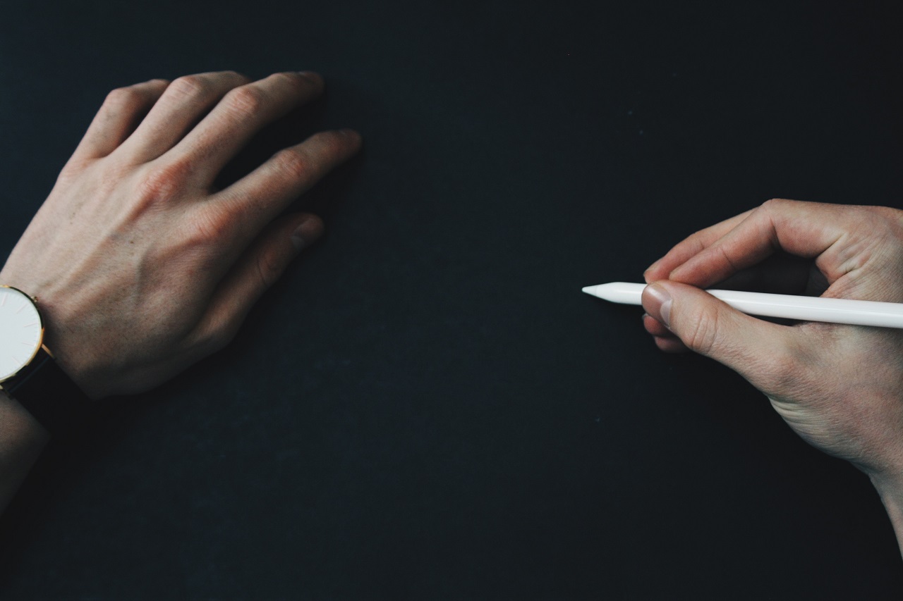 Herausragende Rap Texte schreiben – Rap-Text-E-Book von Benjamin Eidam 2 Zwei Hände mit Stift und Notizblock vor dunklem Hintergrund, symbolisiert Kreativität beim Schreiben