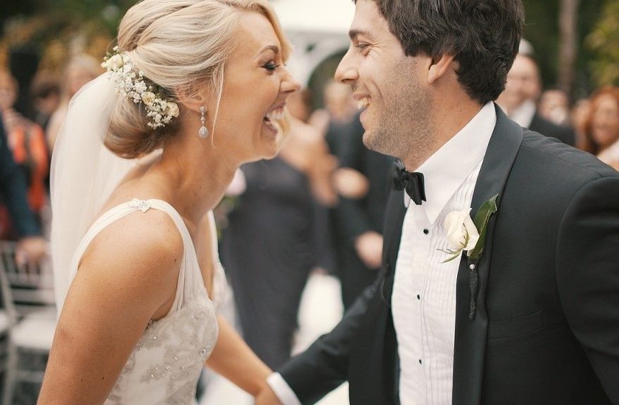 Brautpaar beim Hochzeitstanz mit Kerzenlichtern und Gästen im unscharfen Hintergrund
