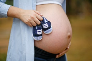 Schwangere Frau hält Baby-Booties, Homöopathie bei Schwangerschaft