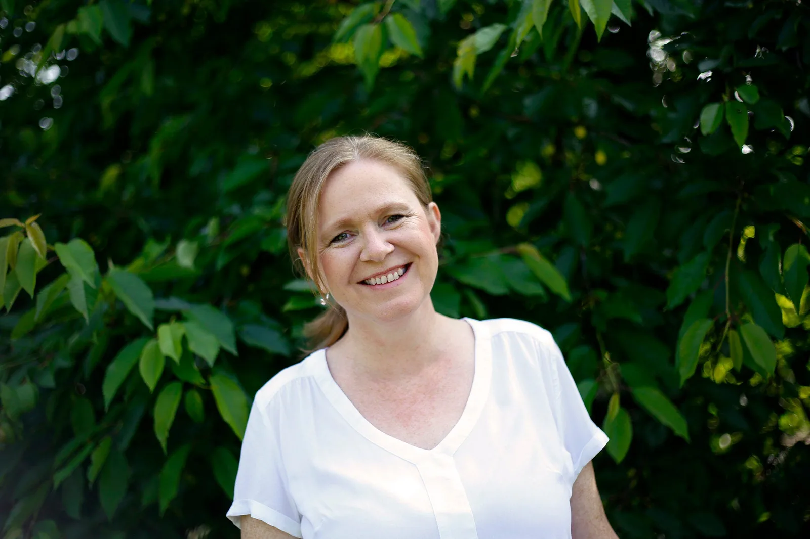 Ulrike Schlüter, Heilpraktikerin, lächelnd vor grünem Hintergrund